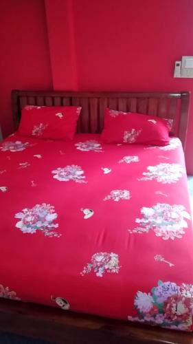 a bed with a red bedspread with flowers on it at Yahle Villa เยห์เล่วิลล่า in Chao Lao Beach