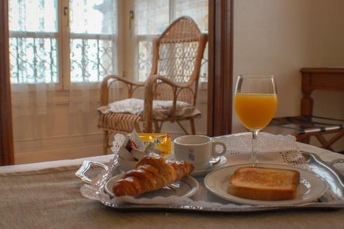 una bandeja de comida para el desayuno y un vaso de zumo de naranja en Hotel Asturias, en Gijón