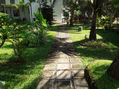 a stone path in a yard with palm trees at Karl Holiday Bungalow in Kalutara