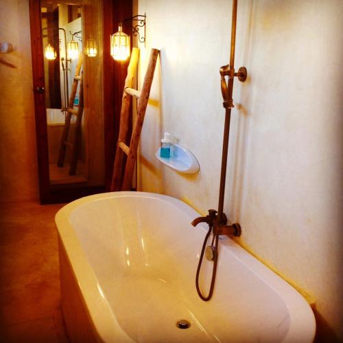 a bath tub in a bathroom with a mirror at Baladin Zanzibar Beach Hotel in Michamvi