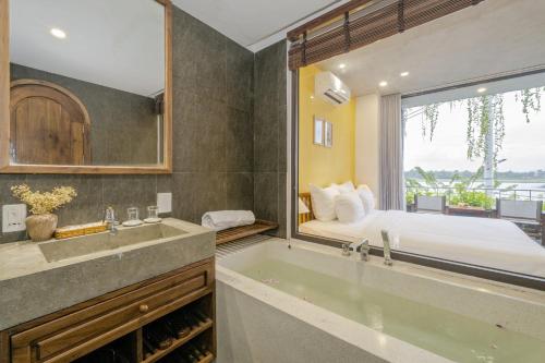 baño con bañera y cama con ventana en The Corner Riverside Villa, en Hoi An