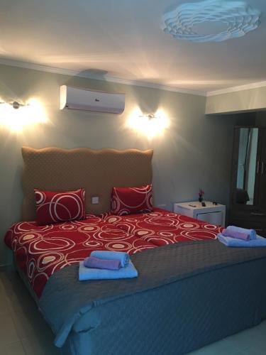 1 dormitorio con 1 cama grande con sábanas rojas y toallas azules en Livadia studio, en Pafos
