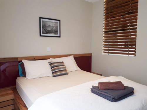 a bedroom with a bed with white sheets and a window at Couples Retreat with Mountain View Near Hobart in Sandford