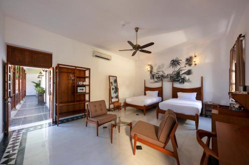 a bedroom with two beds and a ceiling fan at Grand Hotel D'Europe in Puducherry