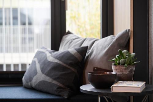 a couch with pillows and a plant on a table at Hotel GUESTapart in Aarhus