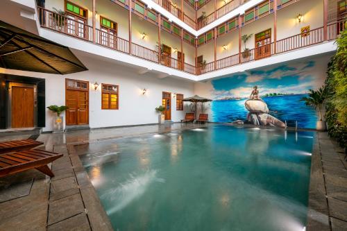 a large swimming pool in a building with a mural at Grand Hotel D'Europe in Puducherry