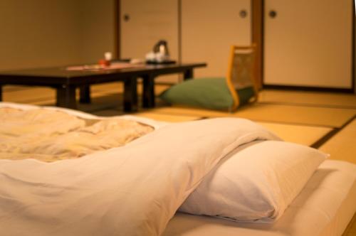 a bed with pillows and pillows in a room at Shosenkaku Kagetsu in Yuzawa