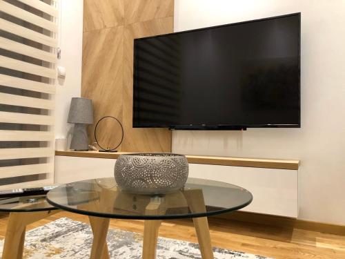 a living room with a table and a flat screen tv at GOMAX Apartmani Zlatibor in Zlatibor
