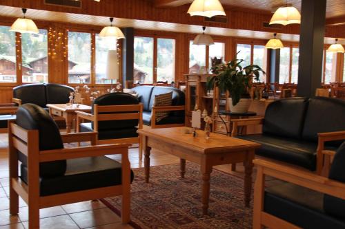 ein Restaurant mit schwarzen Stühlen, Tischen und Fenstern in der Unterkunft Hotel Roc et Neige in Chateau-d'Oex