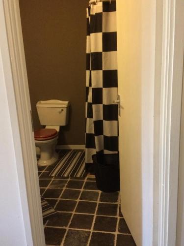 a bathroom with a toilet and a black and white shower curtain at B&B In de Oude Smederij Zaltbommel in Zaltbommel