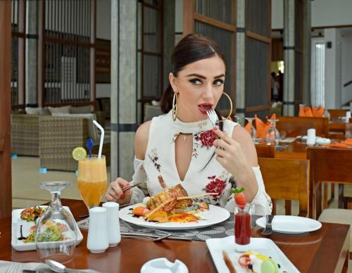 a woman sitting at a table with a plate of food at Goldi Sands Hotel in Negombo