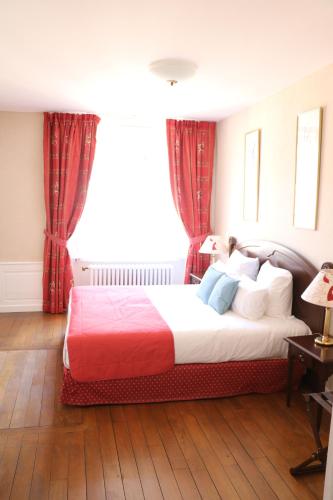 a bedroom with a large bed with red curtains at Hotel D'haussonville in Nancy