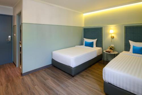 two beds in a hotel room with blue accents at The Mulberry Bangkok Khaosan Road in Bangkok