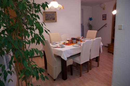a dining room table with a white tablecloth and white chairs at Sebastiana's FeWo in Merzig