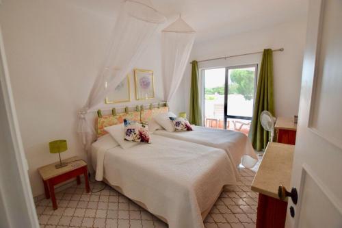 a bedroom with a white bed and a window at Villa Oleander in Vale do Lobo