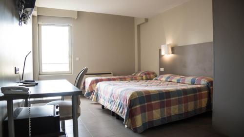 a hotel room with two beds and a desk at Hôtel du Canal in Castelnaudary