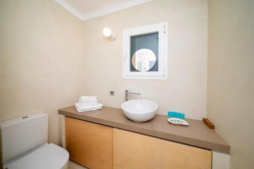 a bathroom with a white sink and a toilet at Apartamentos Roca Plana in Es Pujols