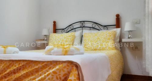 a bed with yellow and white sheets and pillows at Vv CASA JULIANA- Coqueta casa entre montañas. in La Aldea de San Nicolas