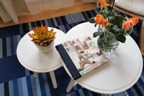 a white table with a vase of flowers and a book at Teubel apartman 5 in Székesfehérvár