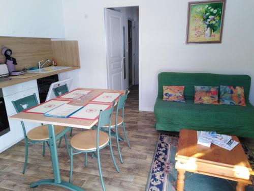 ein Wohnzimmer mit einem Tisch und einem grünen Sofa in der Unterkunft Gite de vacances Residence La Babaute LES ROUSSES in Les Rousses