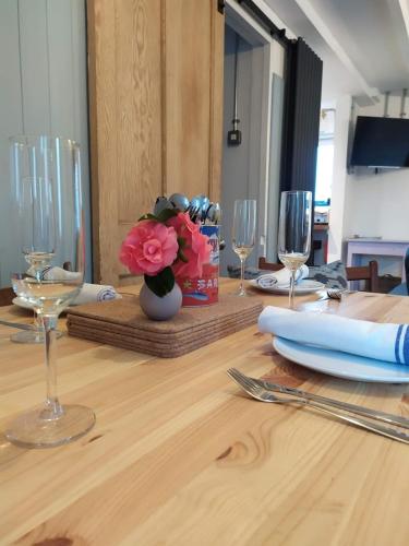 a wooden table with wine glasses and flowers on it at Milking Shed Cottage in Narberth