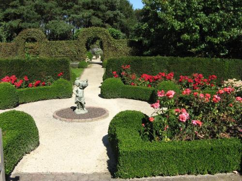 a garden with a statue in the middle of some bushes and flowers at B&B OLEN in Olen
