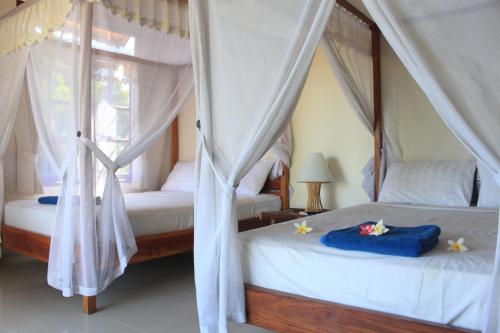 two beds with drapes in a bedroom at Bamboo Bali in Amed