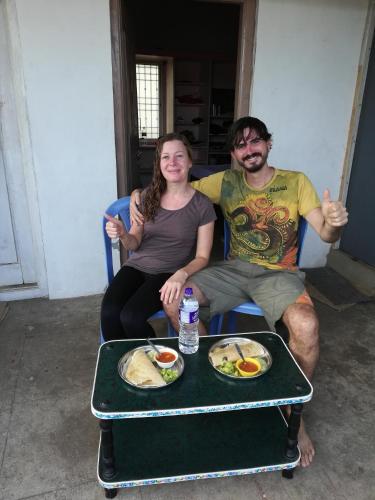 a man and a woman giving thumbs up while sitting at a table at Abhi Homestay Hampi in Hampi