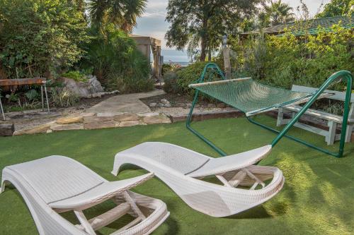 two white chairs and a swing in a yard at Nof Kinneret Cabins in Had Nes