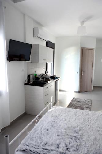 a white room with a bed and a kitchen at Bebas Apartments Nea Karvali in Néa Karváli