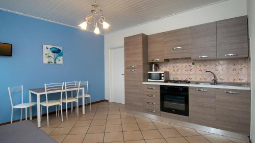 una cocina con armarios de madera y una mesa con sillas. en Acqua Verde Appartamenti, en Peschiera del Garda