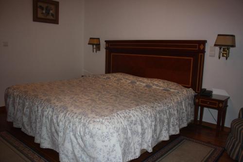 a bedroom with a bed with a wooden headboard and a table at Hotel Sintra Jardim in Sintra