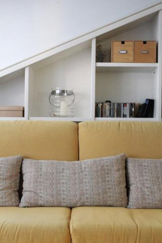 a yellow couch with pillows in a living room at Casa Chiara Plus in Porto Recanati
