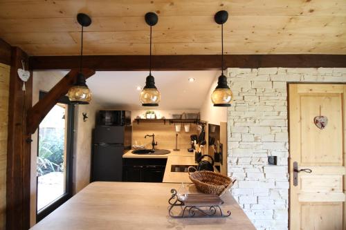 a kitchen with wooden ceilings and a table with a chair at Chalet des 2 moutons in Le Taillan-Médoc