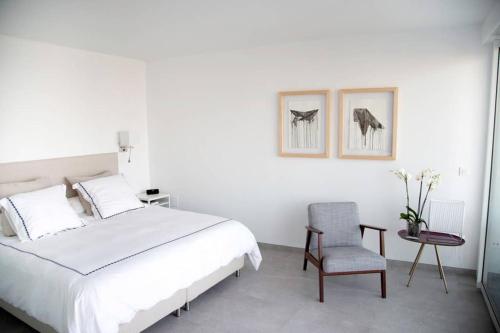 a white bedroom with a bed and a chair at Balcón del Albayzín in Salobreña