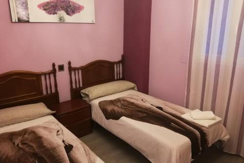 two beds in a room with pink walls at Apartamento Centrico , Wifi + Desayuno in Logroño