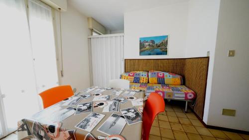a room with a table with orange chairs and a bed at Appartamento Aurora in Lido degli Estensi