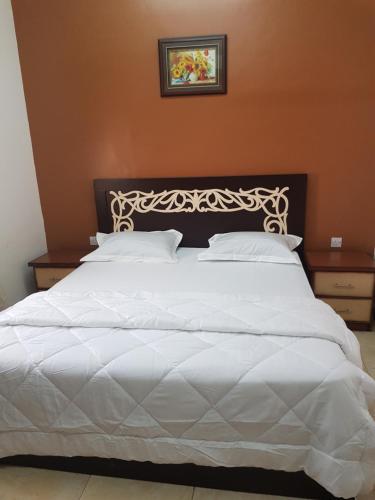 Cama blanca con cabecero negro y almohadas blancas en Beit Almurooj Hotel Apartment, en Salalah