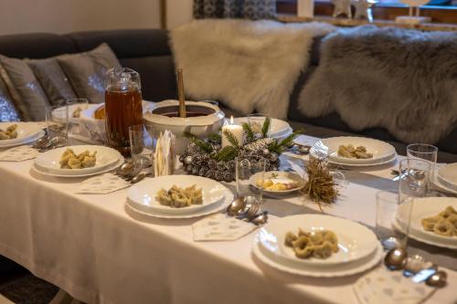 a white table with plates of food on it at Chaty Anety Domki Całoroczne in Solina