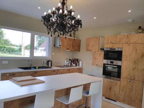une cuisine avec un comptoir blanc et un lustre dans l'établissement La villa d à côté Marigny, Lac de Chalain, à Mont-sur-Monnet