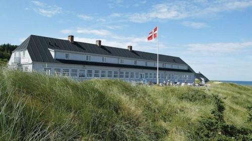 a building on the beach with a red flag at Brovst bed and breakfast in Brovst