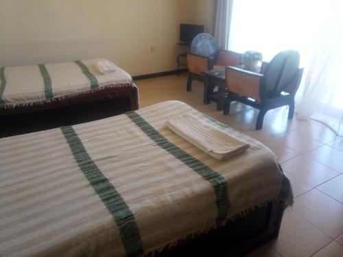 a room with two beds and a chair and a desk at Honey Land Hotel Lalibela in Lalībela