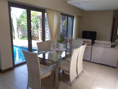 a dining room with a glass table and chairs at Villa Athena at Grand Baie with private pool in Grand Baie