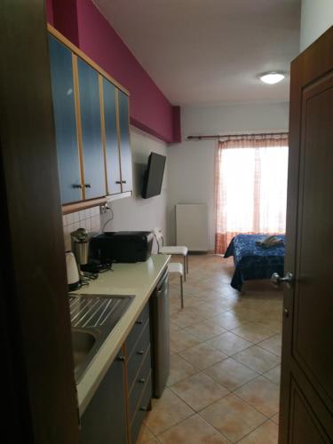 a kitchen with a counter and a room with a bed at G M 6 ROOMS KENTRO in the heart of the city in Larisa