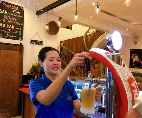 a man is making a drink at a bar at Poolside Villa in Phnom Penh