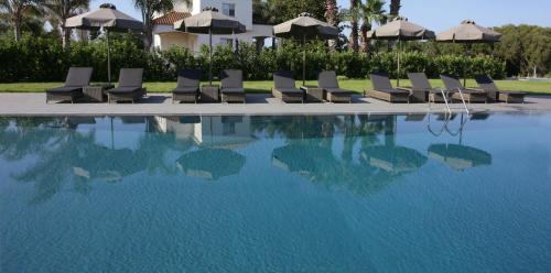 a group of chairs sitting next to a swimming pool at Lagouvardos Village Hotel in Marathopoli
