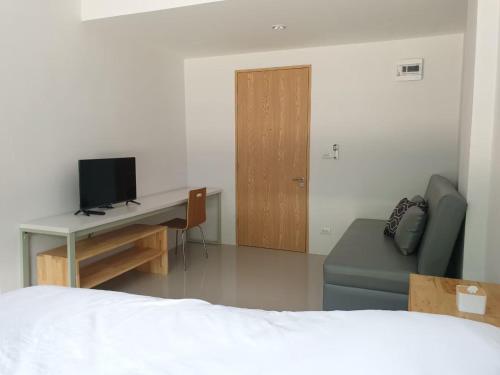 a bedroom with a bed and a desk with a television at NK place Phetchaburi in Ban Nong Som