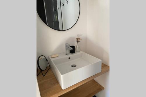 a bathroom with a white sink and a mirror at Le clos du Mesnil, Logement totalement indépendant in Le Tourne