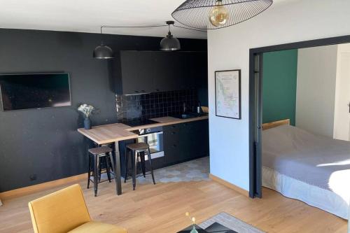 a bedroom with a bed and a kitchen with a table at Le clos du Mesnil, Logement totalement indépendant in Le Tourne