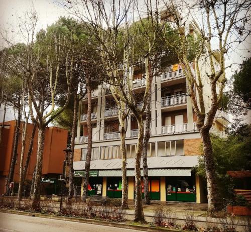 a tall white building with trees in front of it at Bilocale Marina Romea in Marina Romea